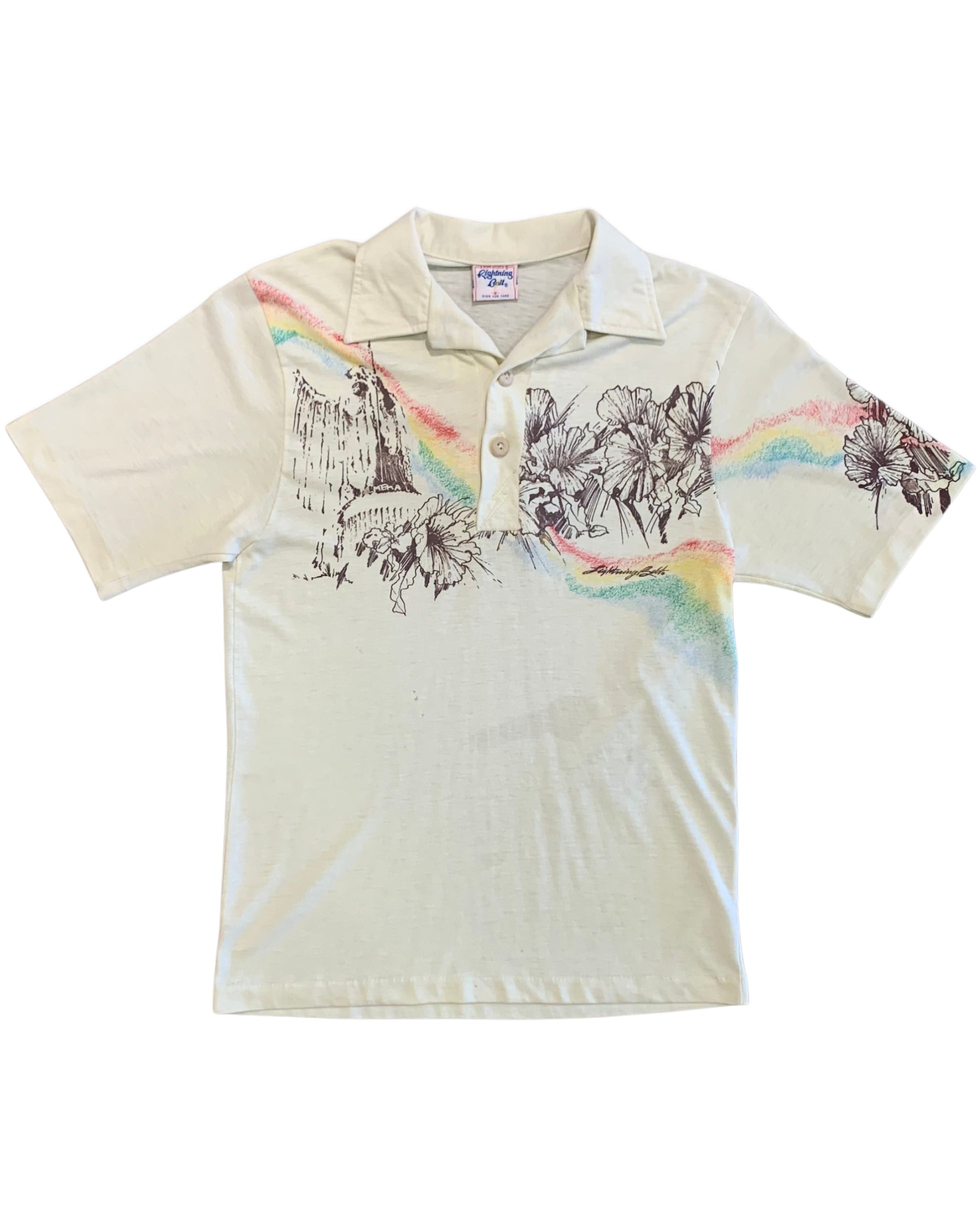 Front view of a cream Lightning Bolt short-sleeve polo with black floral and landscape artwork and rainbow-colored accents across the chest and sleeves.
