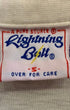 Close-up of a Lightning Bolt A Pure Source woven label marked size Small inside a cream polo shirt.
