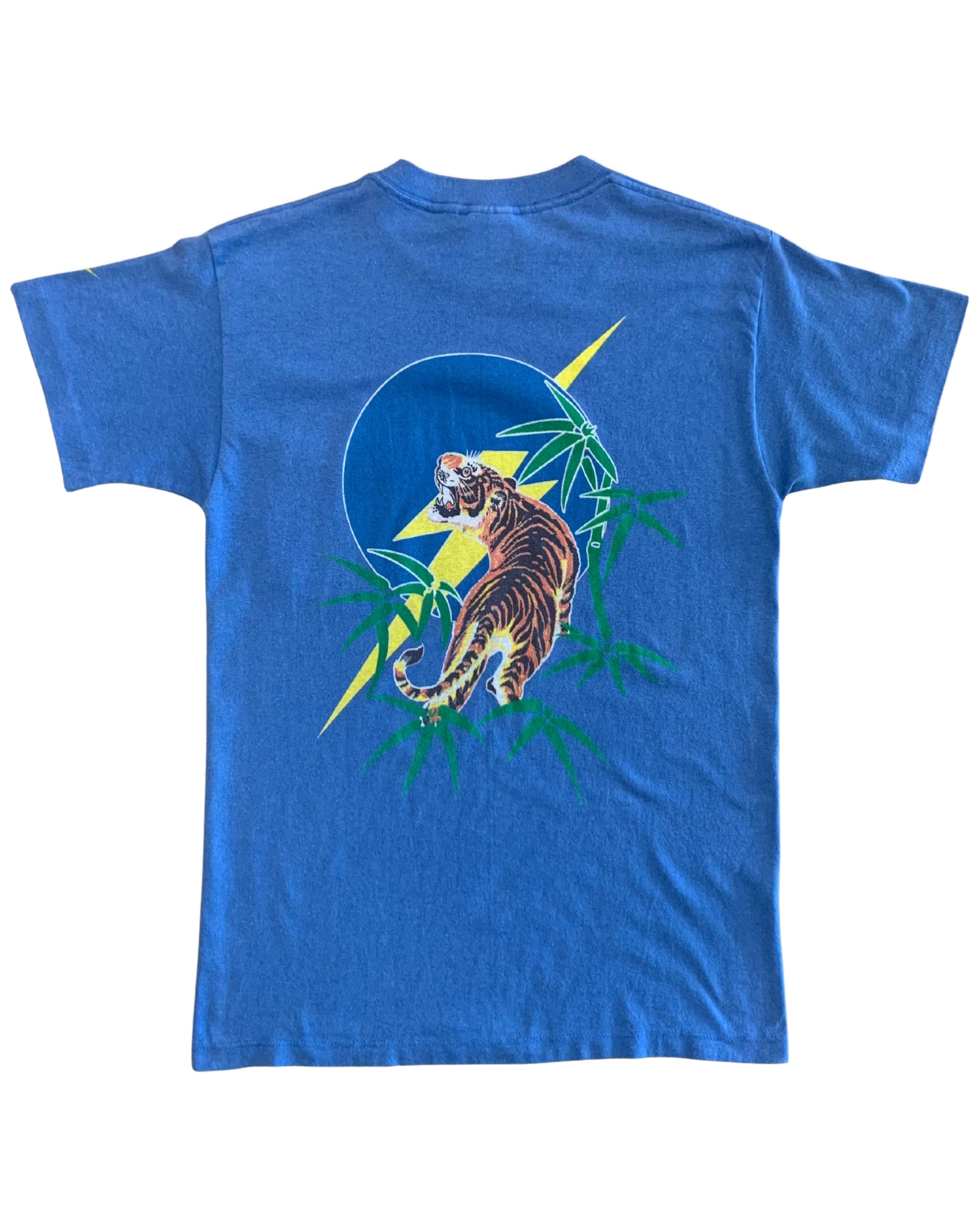 Back view of a rare vintage 1970s Lightning Bolt blue graphic tee showing a detailed roaring tiger print framed by green bamboo and a yellow lightning bolt logo.