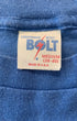 Close-up of the original 1970s woven neck label reading Lightning Bolt Medium 38-40 Made in U.S.A. on a heather blue cotton knit shirt.
