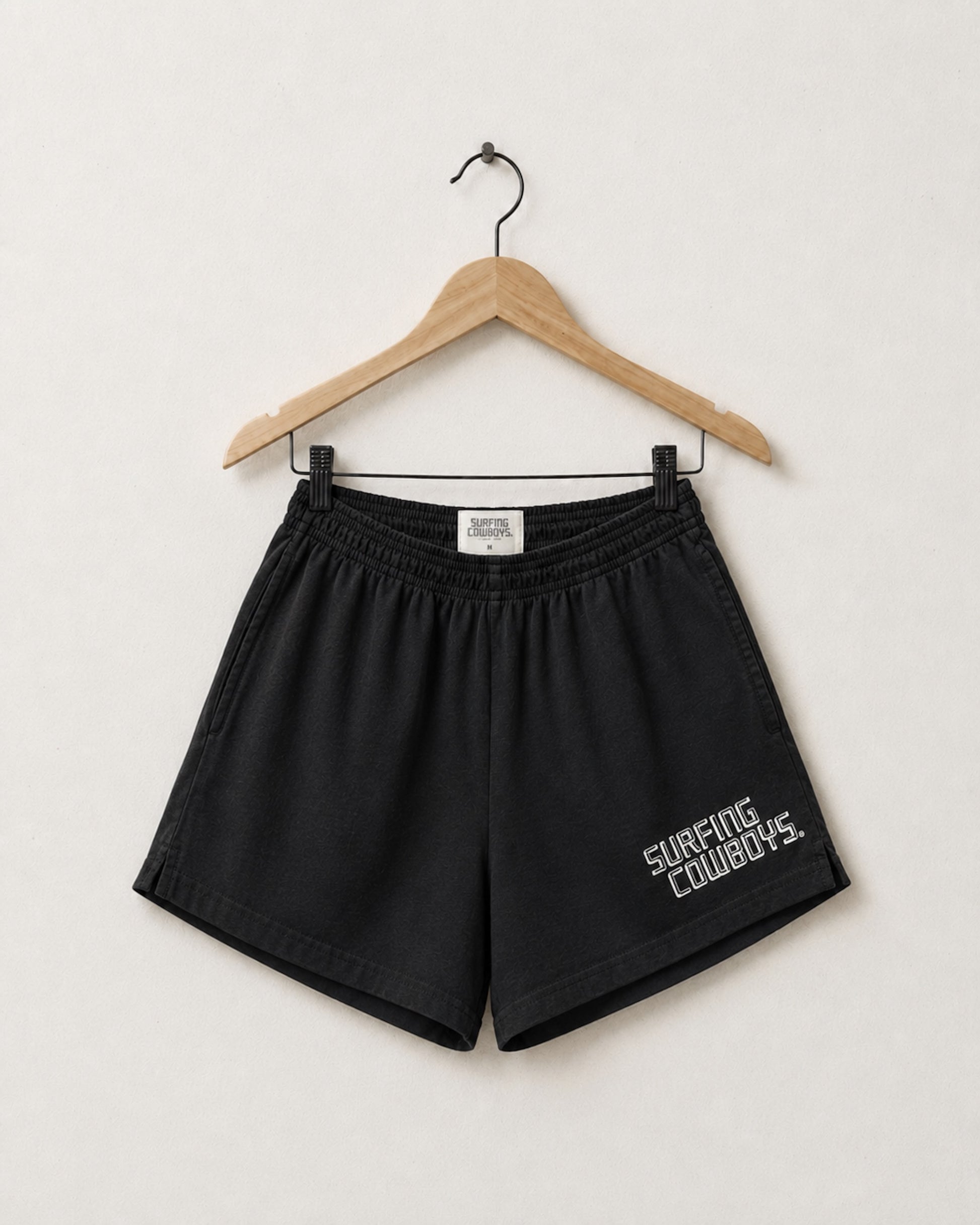 Surfing Cowboys washed black cotton gym shorts with elastic waistband, side pockets, and small logo printed on the front.