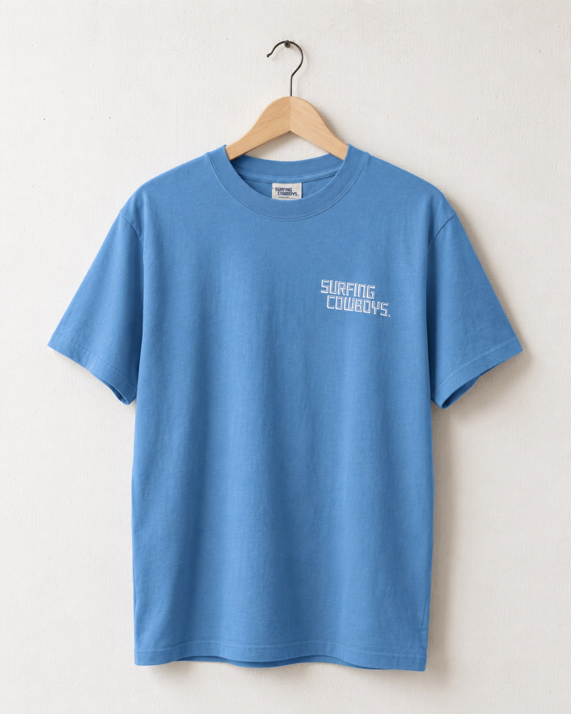 Front of Surfing Cowboys Logo high crew T-shirt in Washed Blue with small front chest logo and larger back logo print both in white ink.