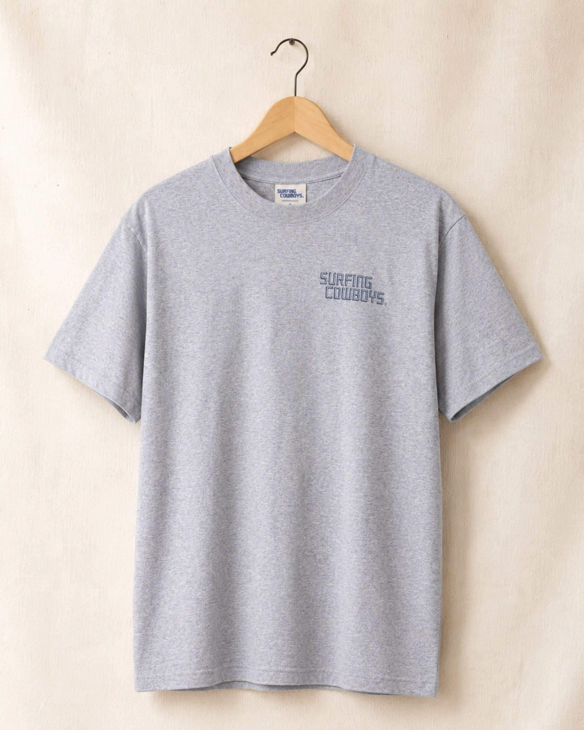 Front of Logo T in Heather Grey hanging on hanger with Surfing Cowboys Logo on chest 