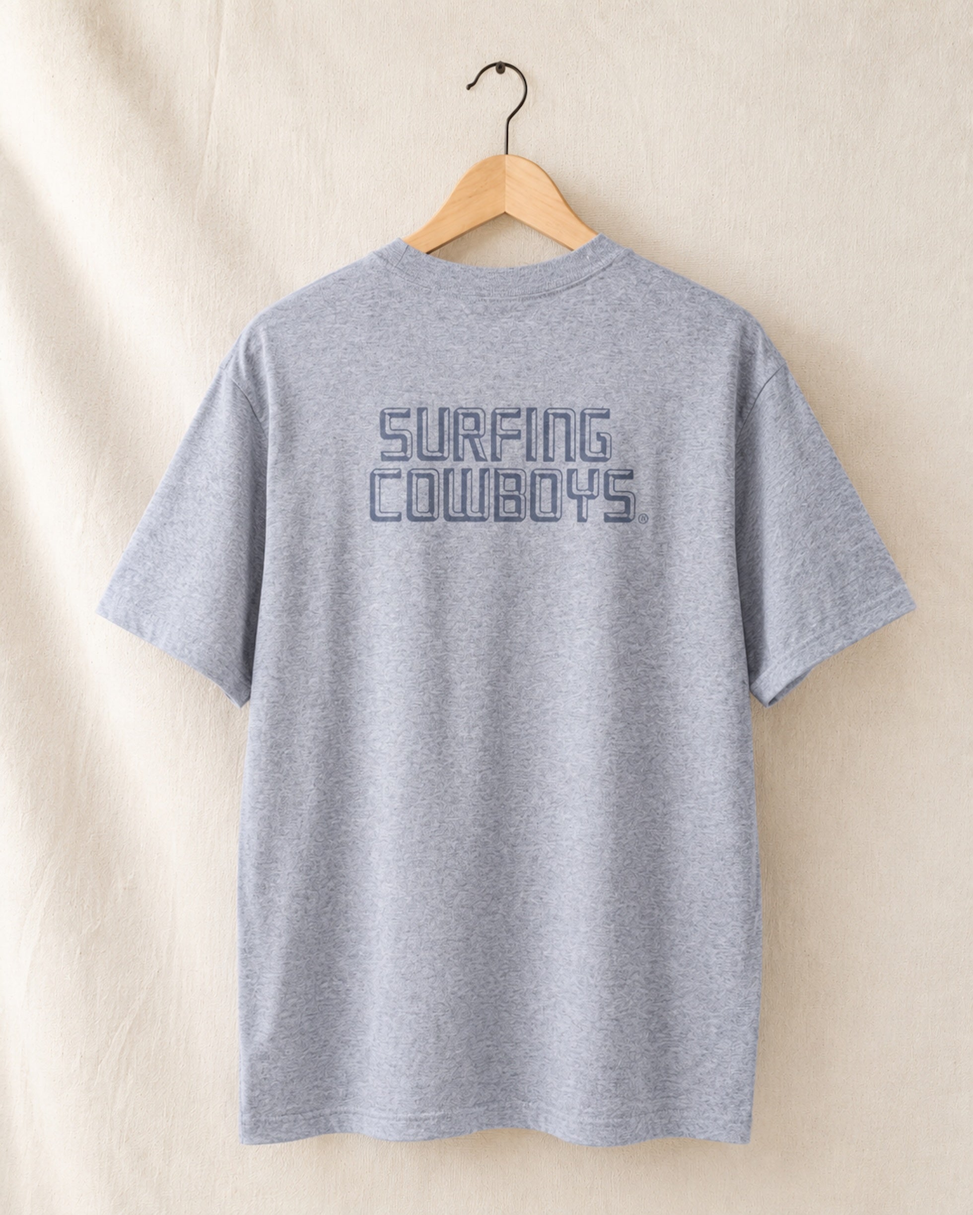 Back of Logo T in Heather Grey hanging on hanger with Surfing Cowboys Logo on center back.
