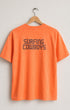 Faded orange t-shirt with 'Surfing Cowboys' text on a hanger against a light gray background