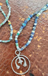 Necklace with blue beads and a silver pendant on a textured brown surface