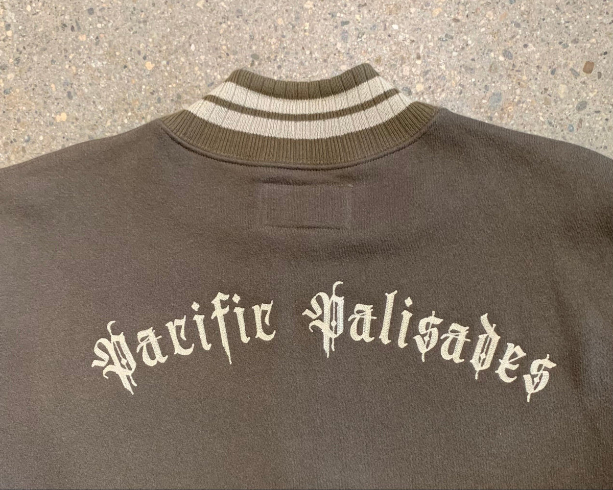 Close-up view of the striped cream and brown ribbed neck and the back featuring cream Surfing Cowboys branding centered and embroidered.

