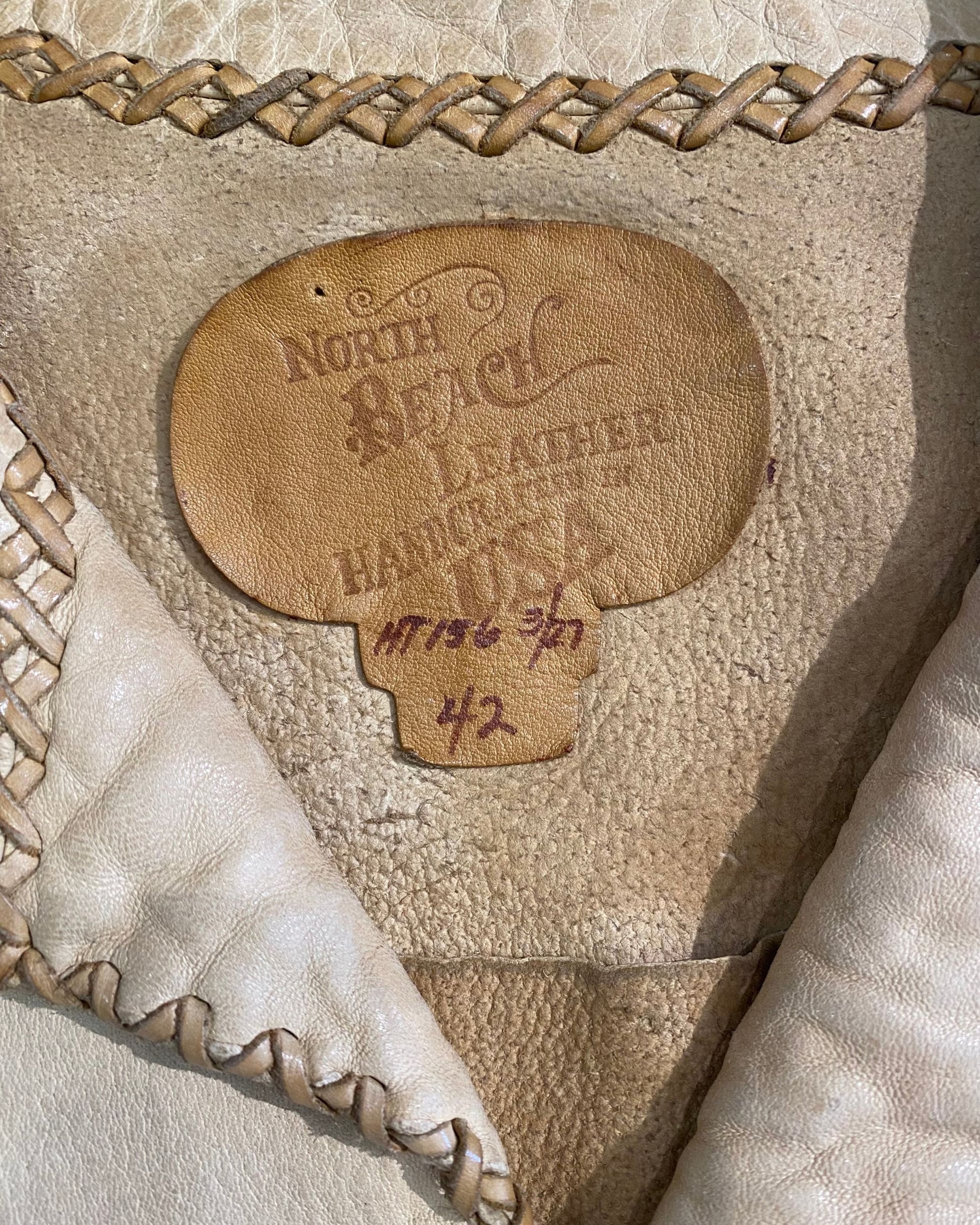 Close-up of North Beach Leather label with handwritten size and serial number.