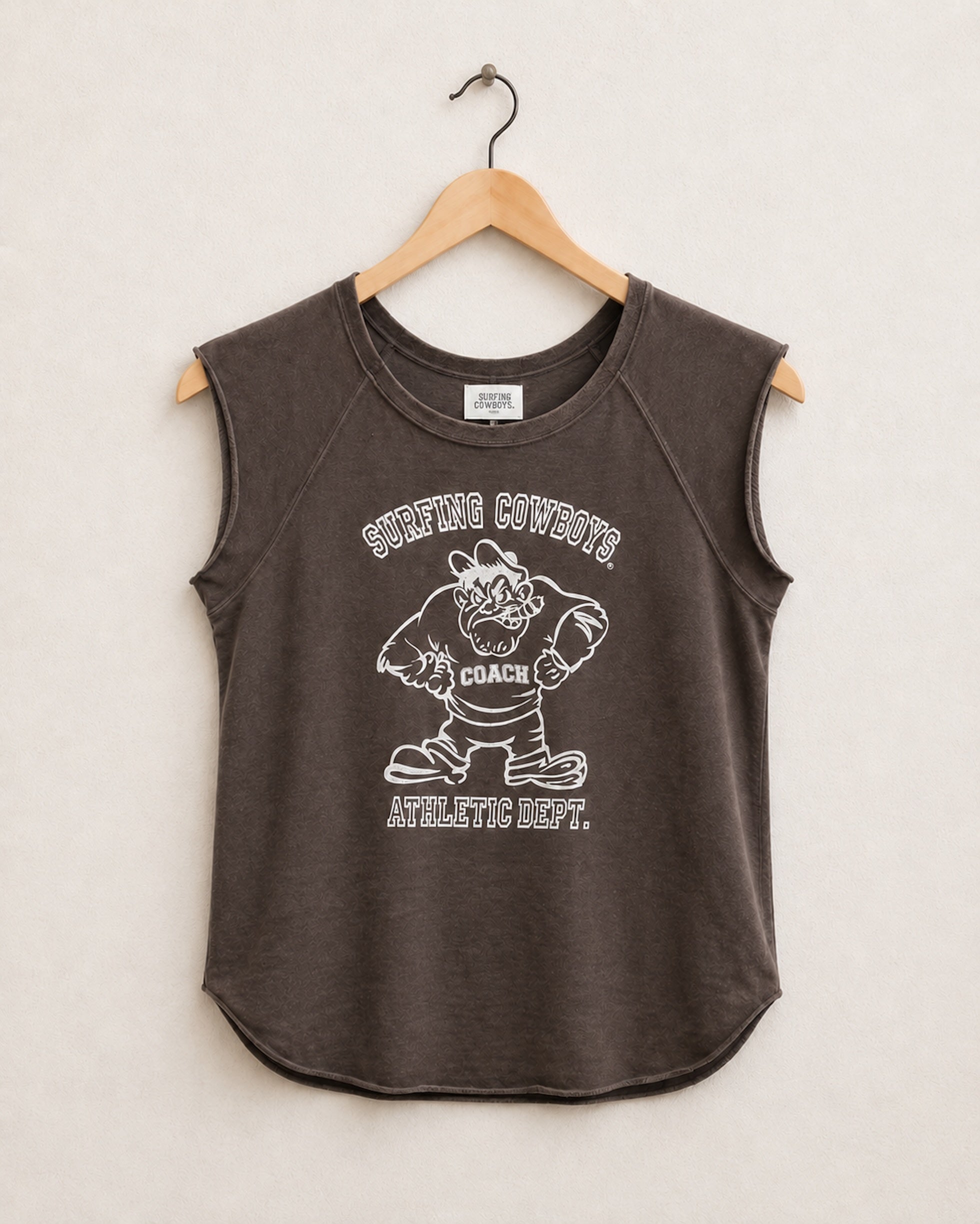 Brown sleeveless shirt with graphic design on a hanger against a beige background