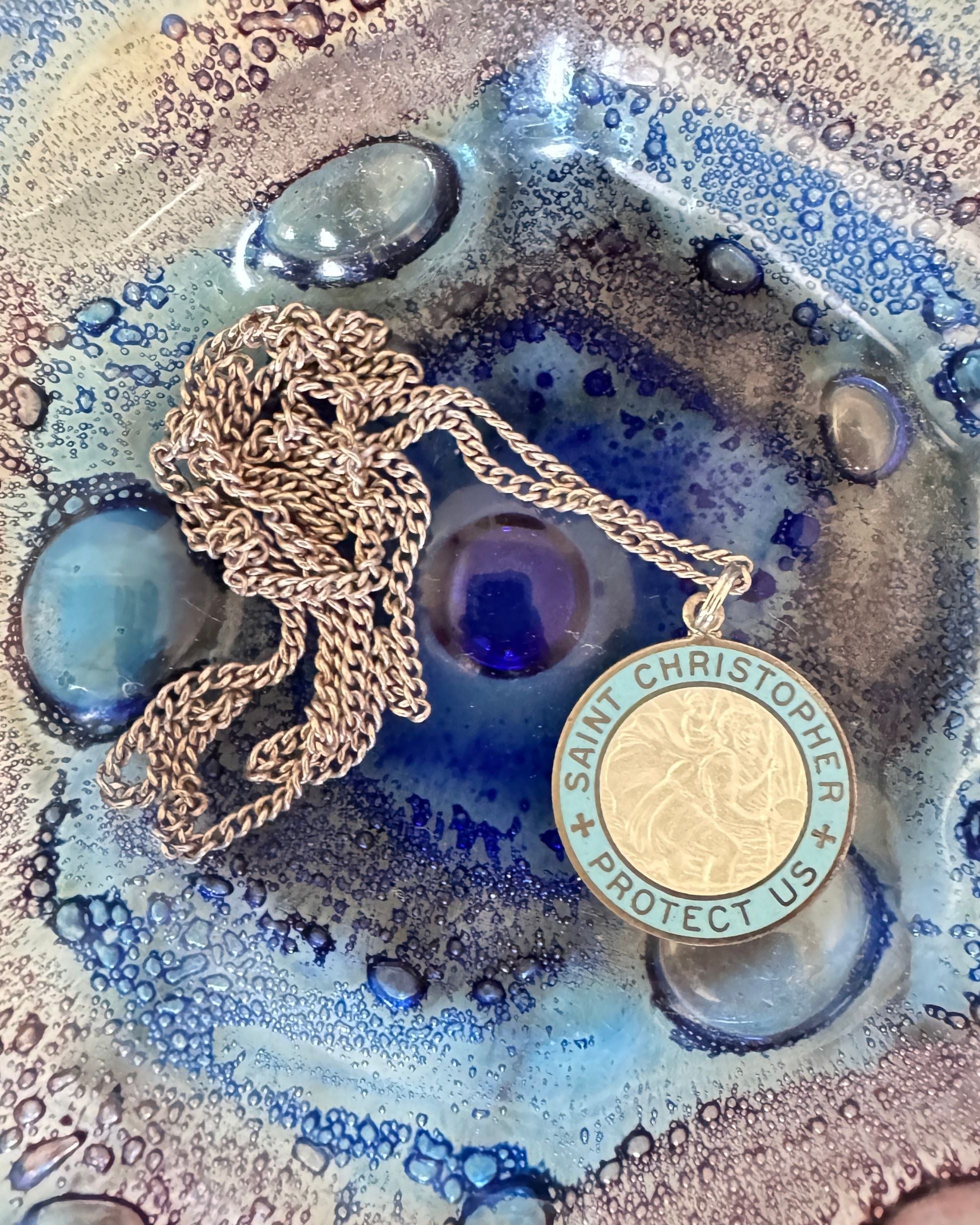 Vintage blue and white enamel St. Christopher pendant on sterling chain - displayed in art glass dish.