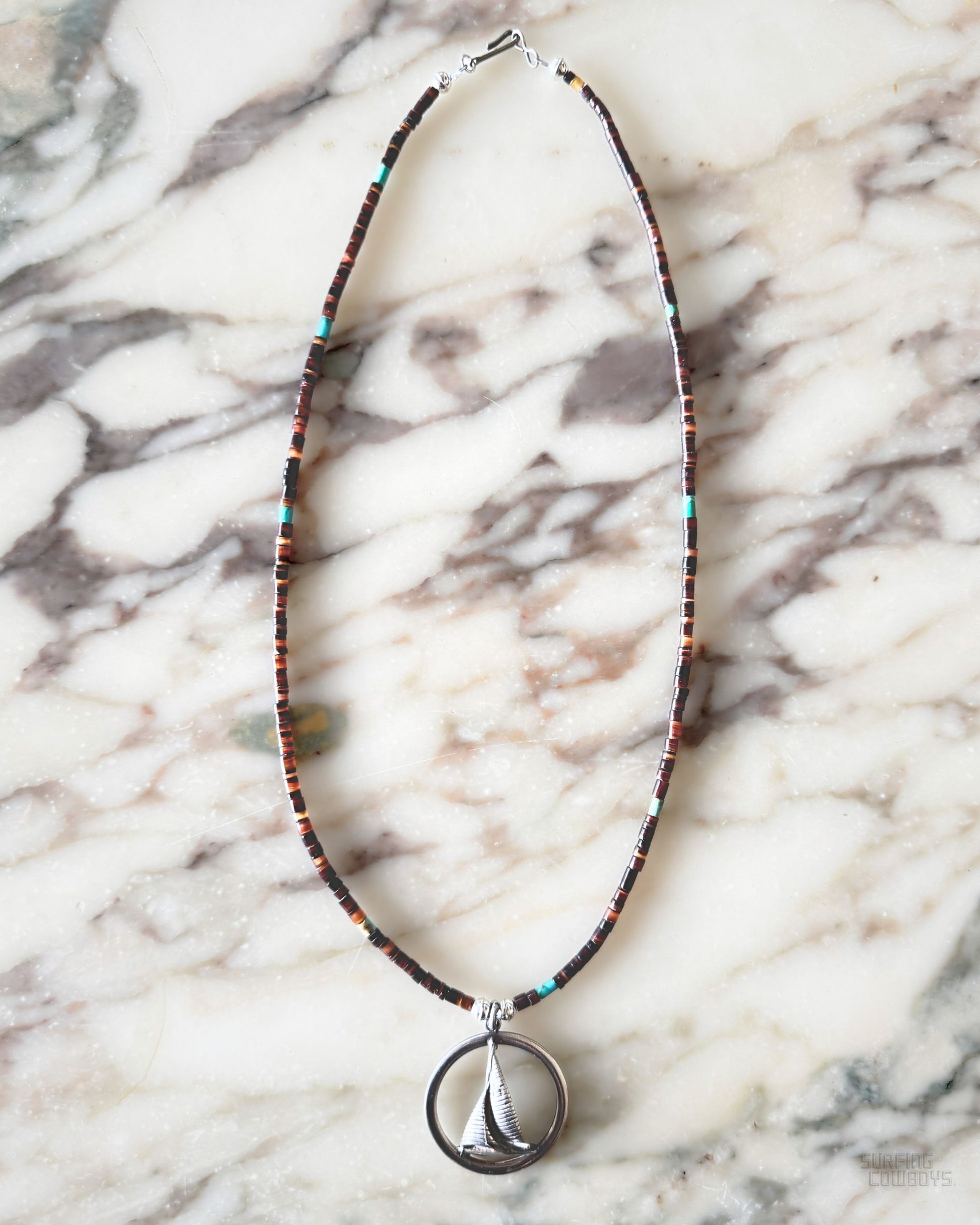 Sterling silver sailboat pendant on 21-inch vintage brown shell heishi bead necklace with turquoise highlights.