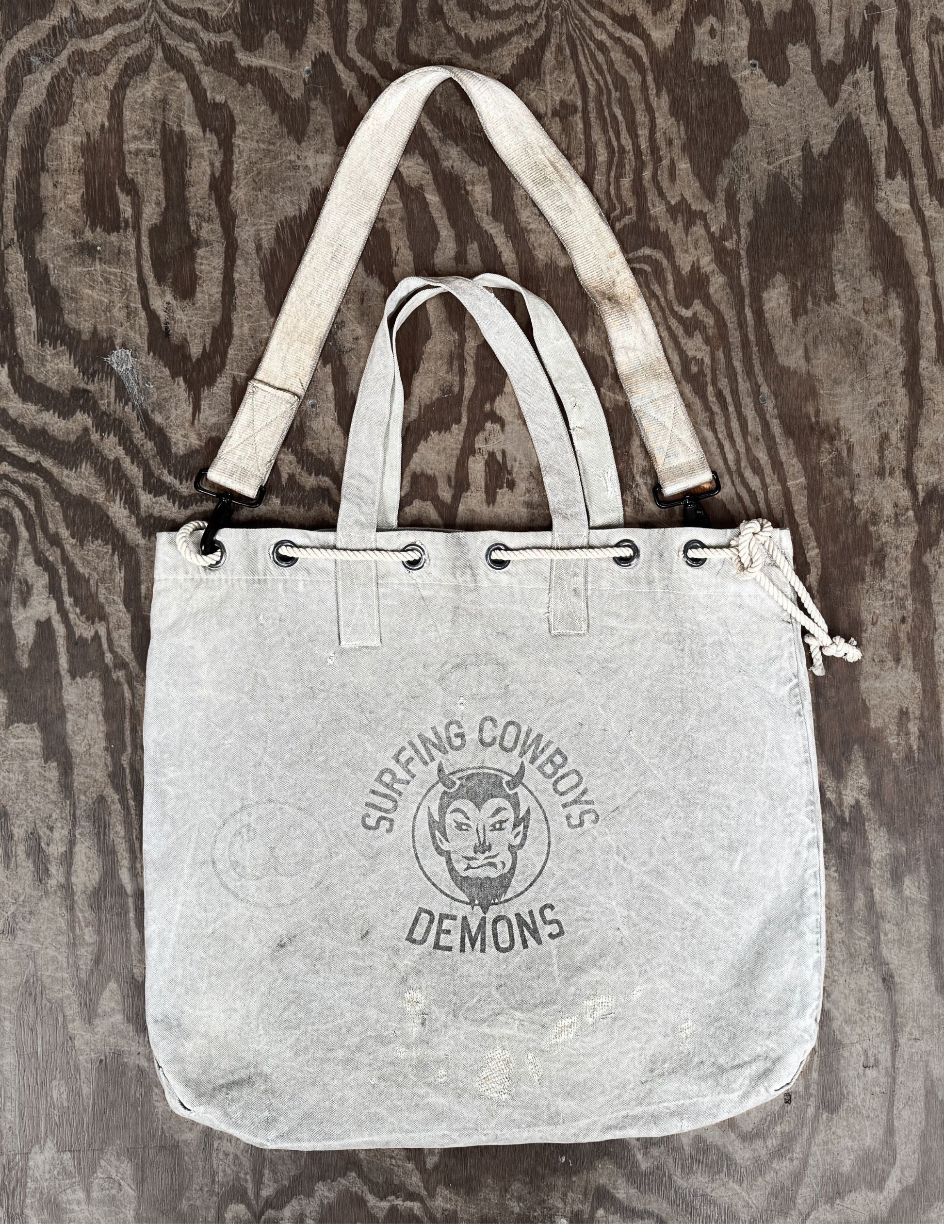 Flat front view of Surfing Cowboys Demons tote with handles and crossbody strap.