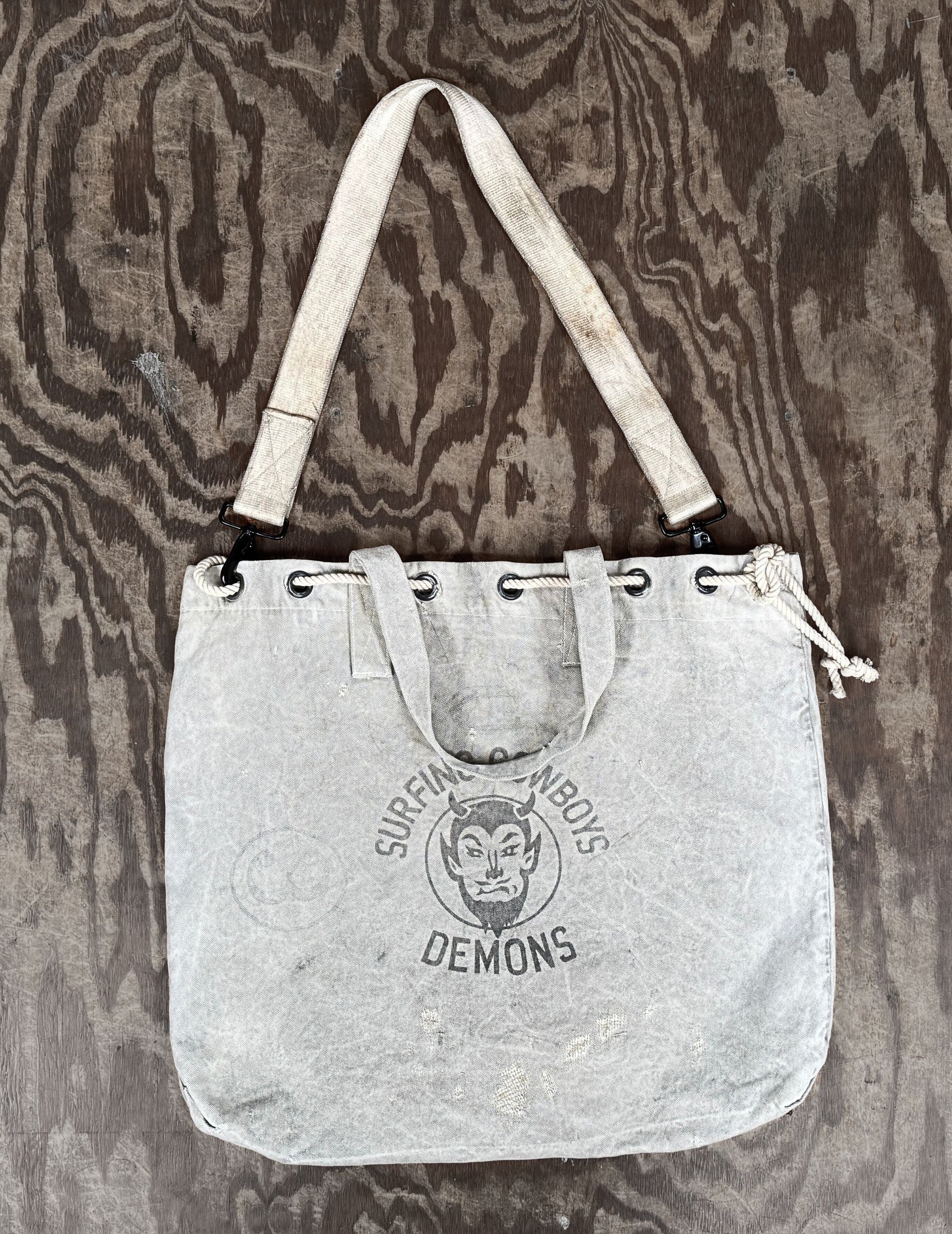 Top view of Surfing Cowboys Demons canvas tote bag showing strap hanging naturally.