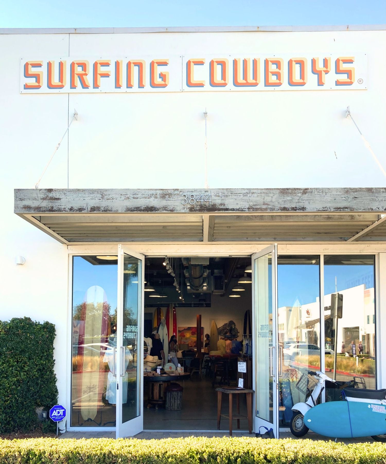 Storefront with 'Surfing Cowboys' sign above glass doors