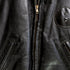 Details of zipper and leather patch 1950s Taubers black horsehide leather jacket with lace-up sides, Western-inspired yoke, and visible signs of wear.
