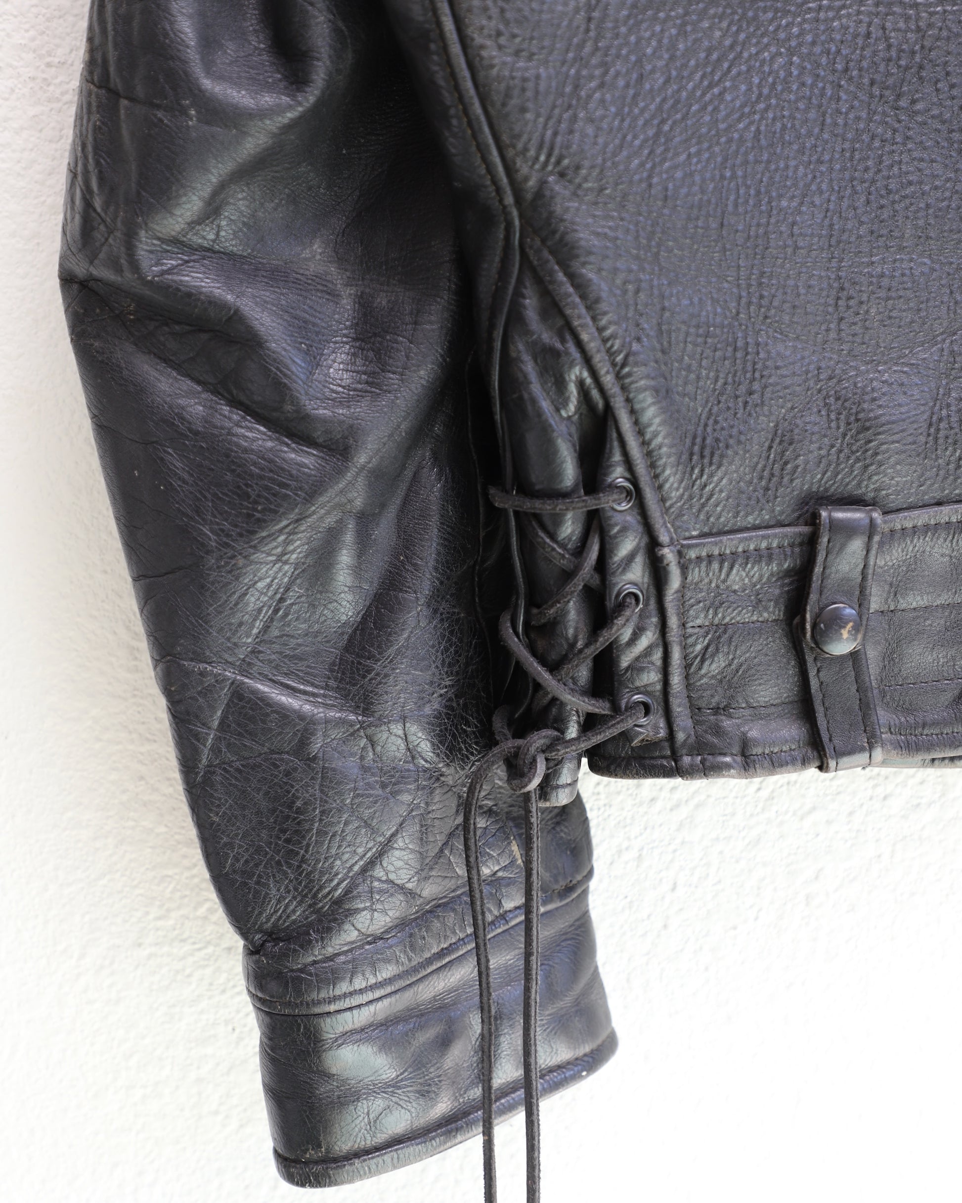 Lace, sleeve and cuff detail 1950s Taubers black horsehide leather jacket with lace-up sides, Western-inspired yoke, and visible signs of wear.
