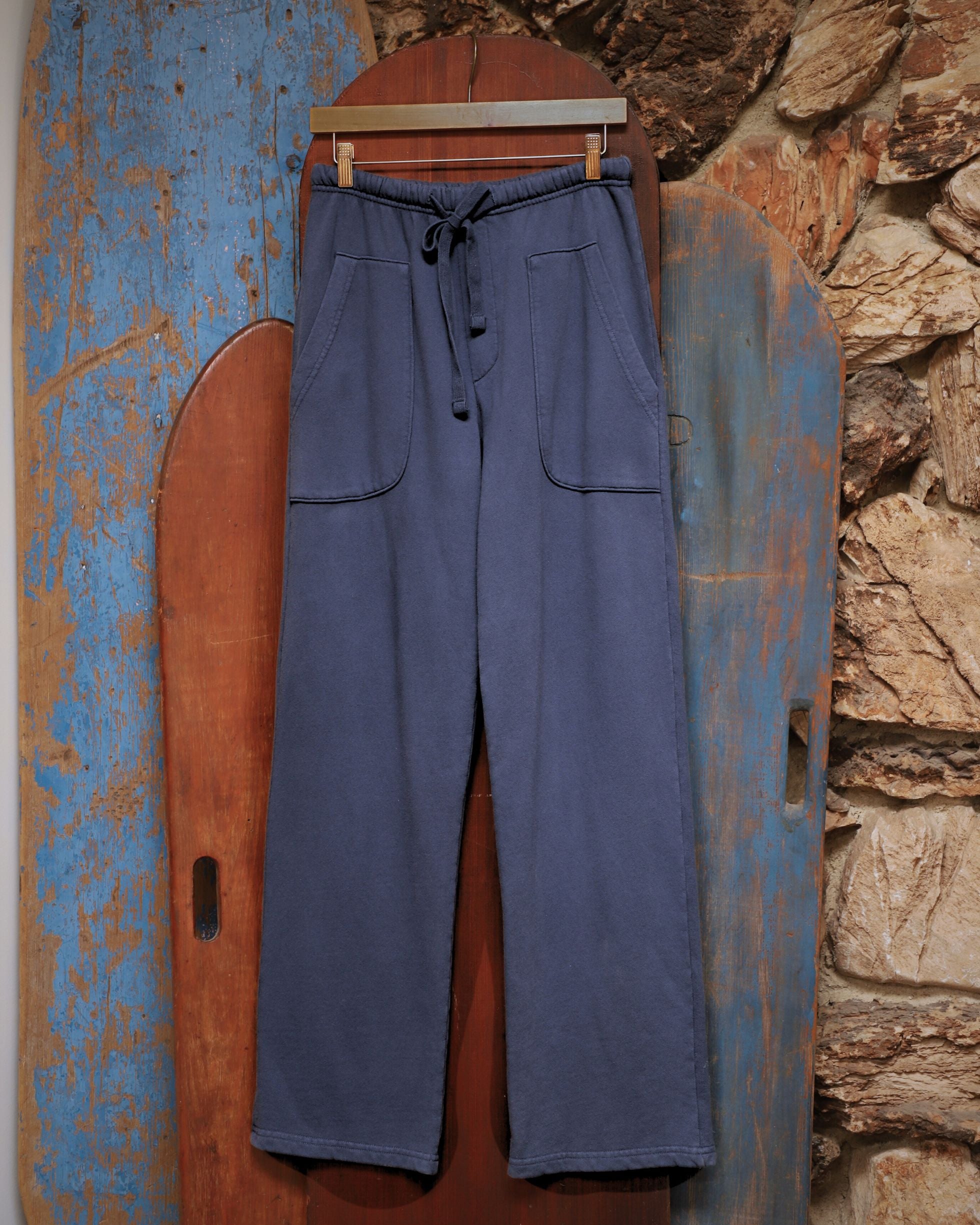 Styled photo of The Weekender Pants hanging against vintage wood surfboards.
