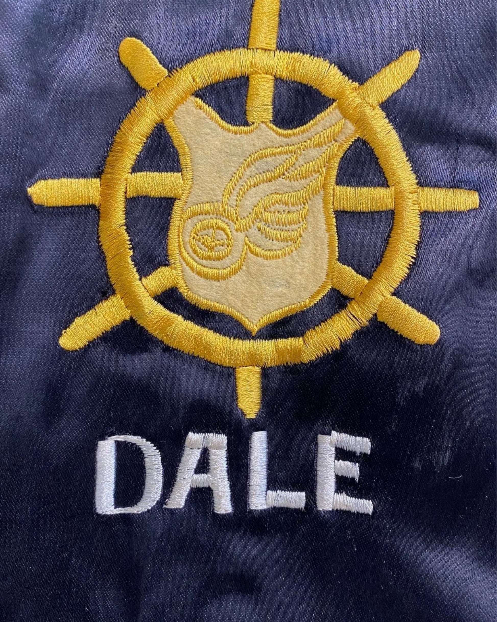 Detail of yellow wheel and wing military emblem with DALE name.