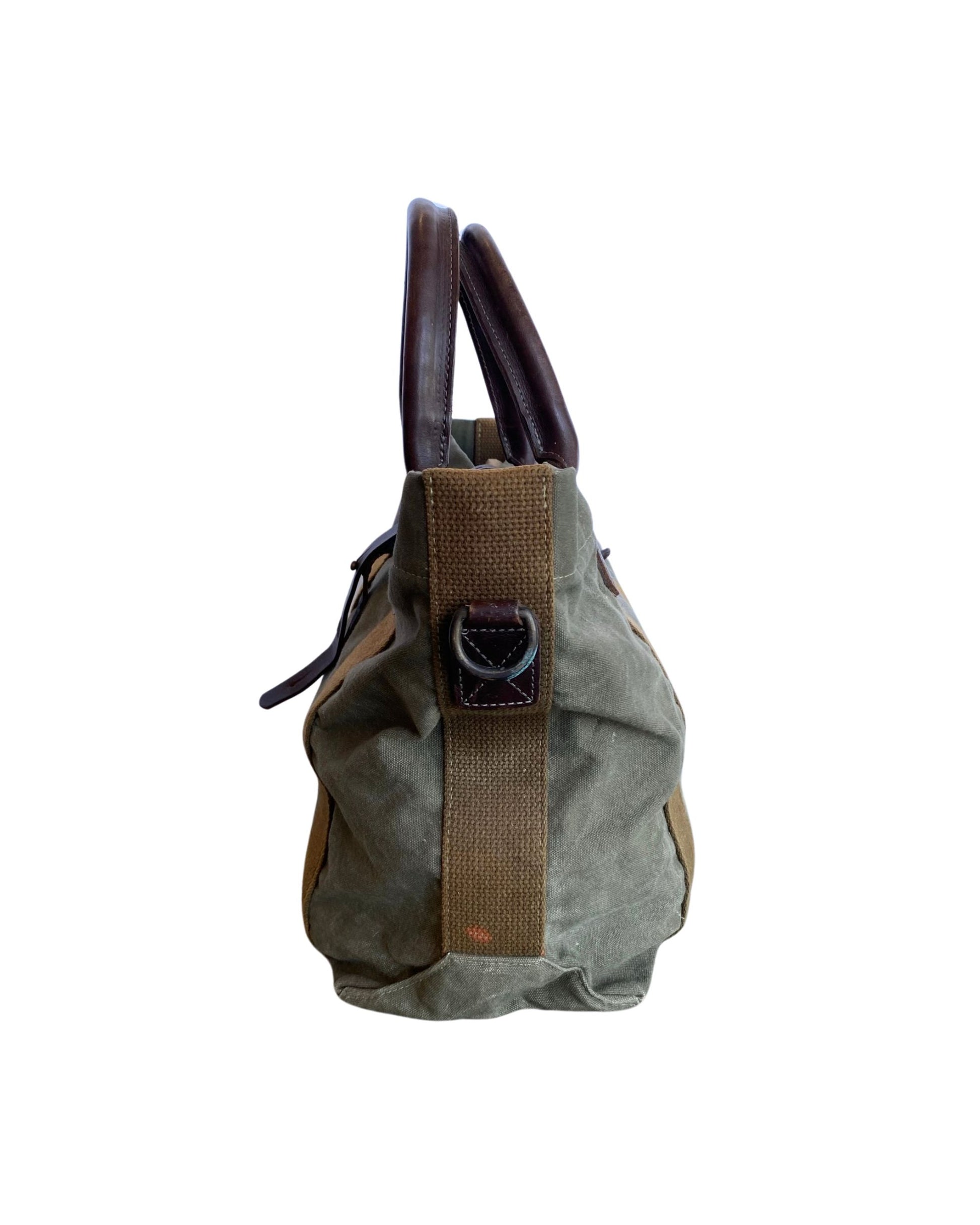 Vintage olive green canvas military tote with brown leather handles and webbing straps, interior zip pocket shown. Side.
