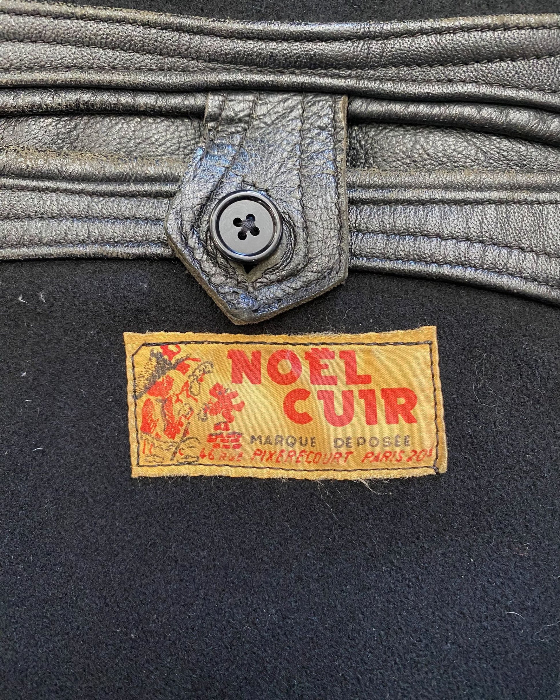 Close-up of original Noël Cuir Marque Déposée label, 46 Rue Pixérécourt Paris 20e, with leather interior button tab detail.
