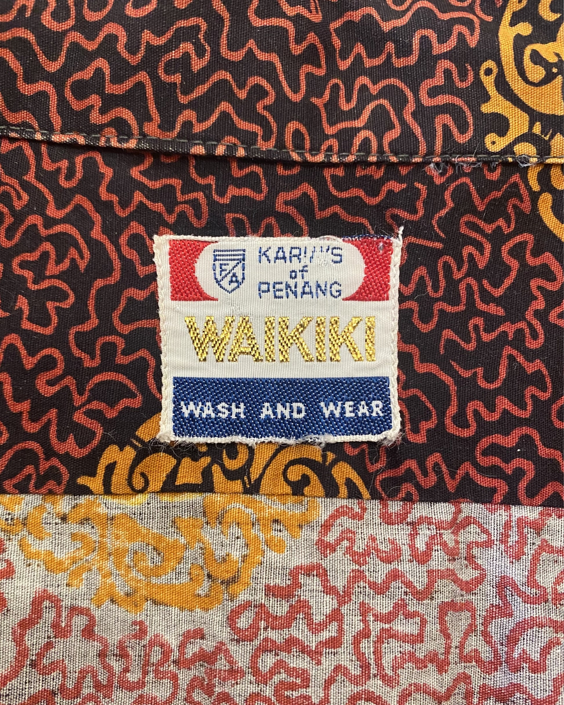 Neck label of vintage 1960s Kary’s of Penang Waikiki print shirt in maroon and gold with dragon border and medallion pattern.