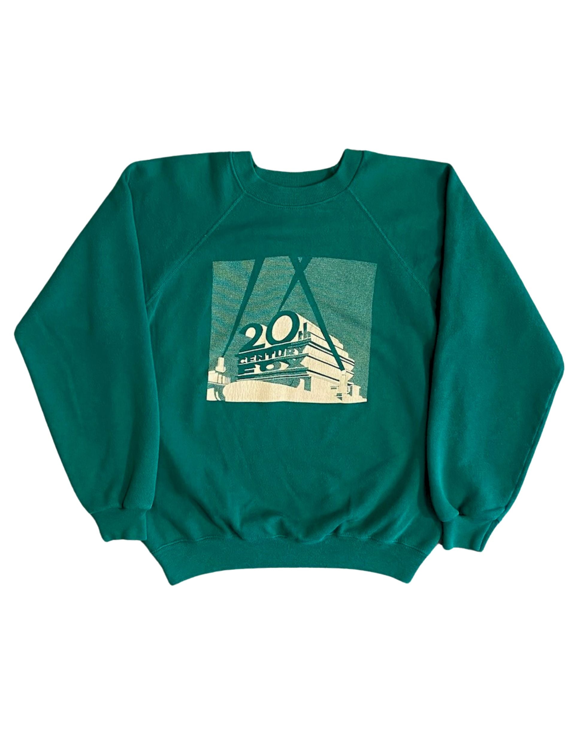 Front view of vintage 1980s 20th Century Fox green raglan crewneck sweatshirt with cream halftone screen print logo graphic, on white background.