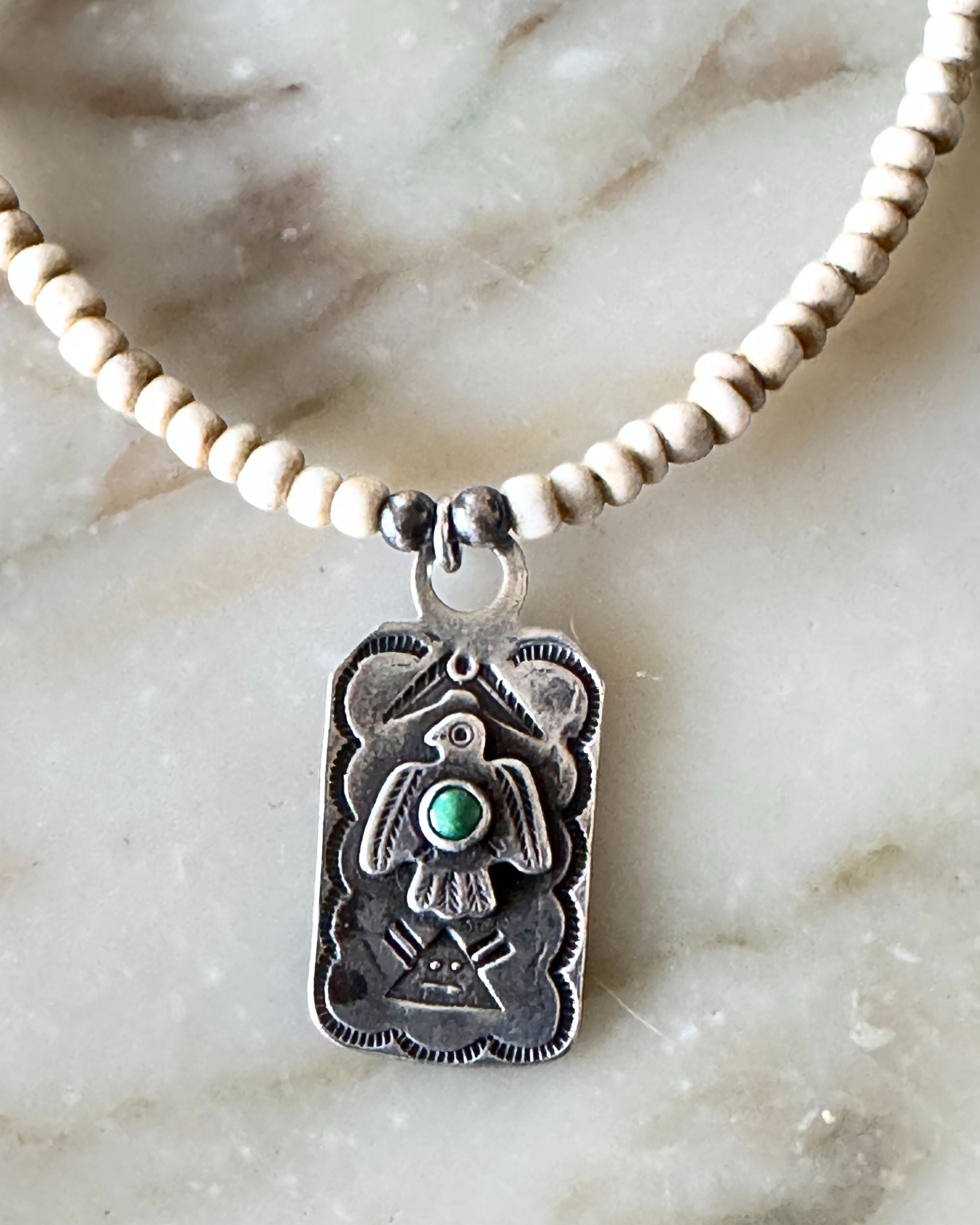 Detail view of vintage Fred Harvey Thunderbird pendant with turquoise on newly strung ceramic bead necklace.