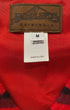 Label detail of Pendleton Originals wool cotton vest made in USA on red background.

