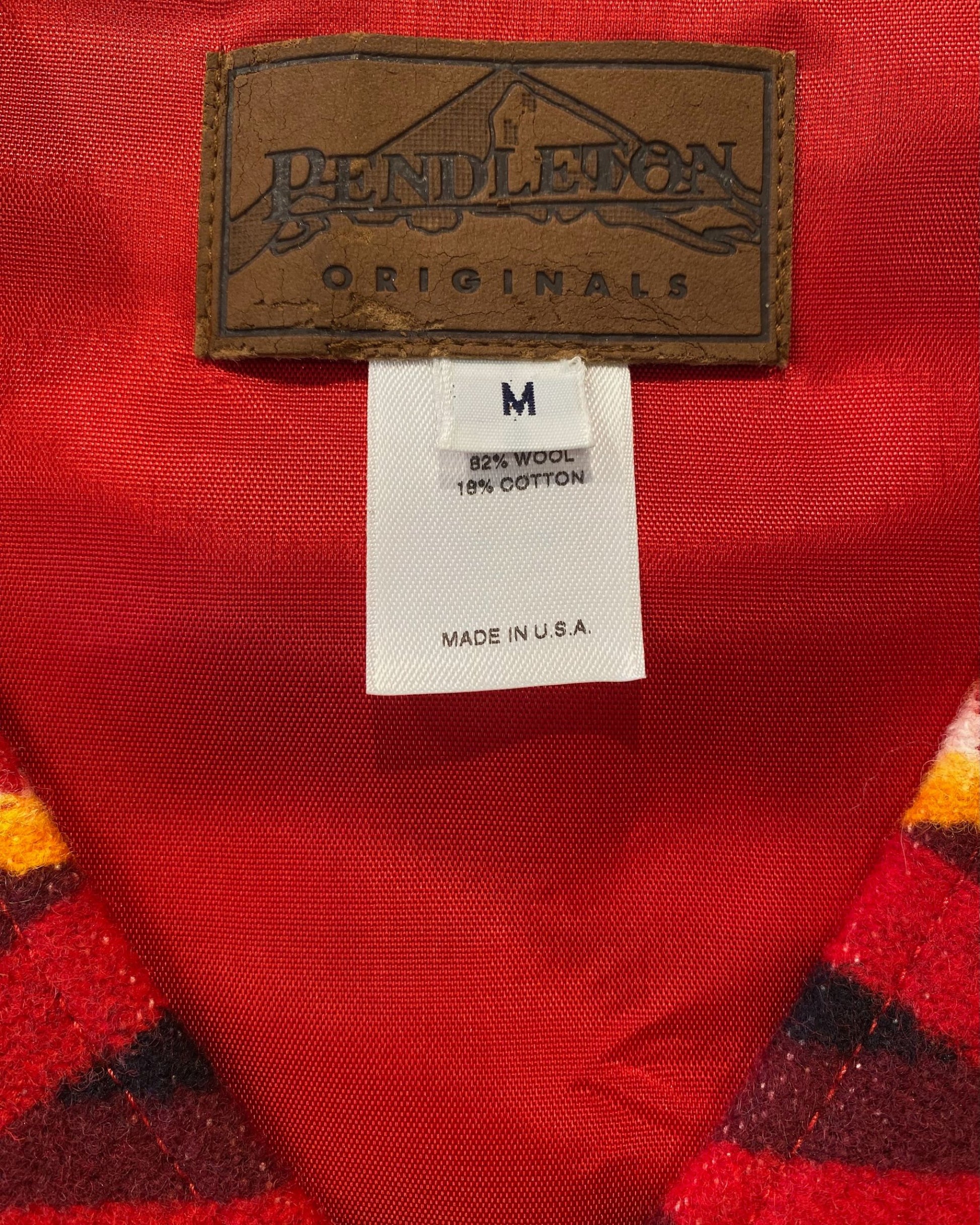 Label detail of Pendleton Originals wool cotton vest made in USA on red background.
