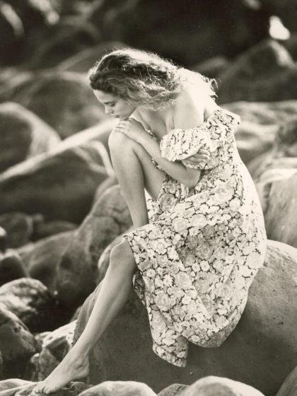 Woman With Dress Sitting On Rocky Beach