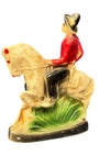 Carnival cowboy figure on horseback with red shirt and black mask.