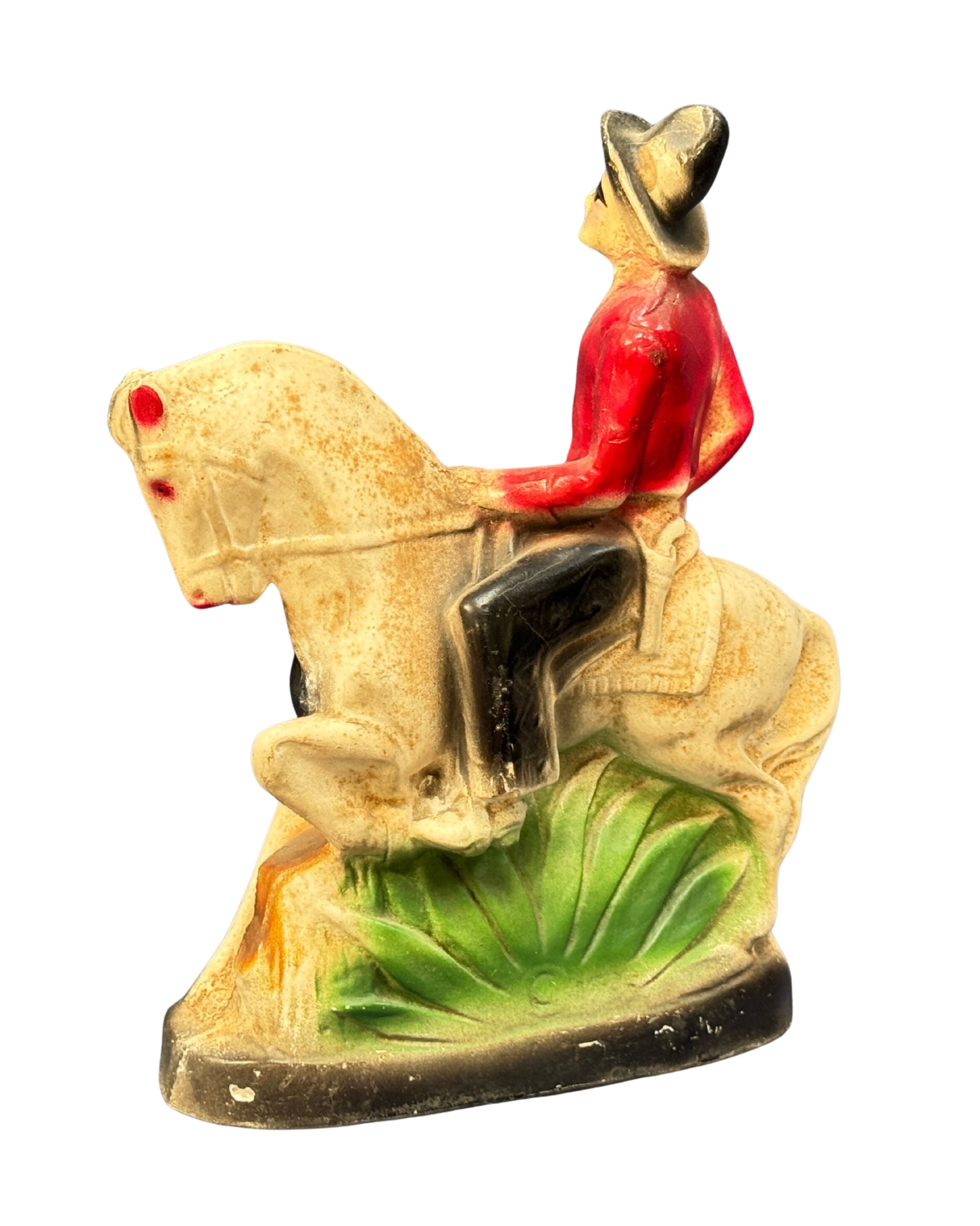 Carnival cowboy figure on horseback with red shirt and black mask.