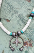 Close-up of vintage sterling silver naja-style pendant with turquoise and white beads.
