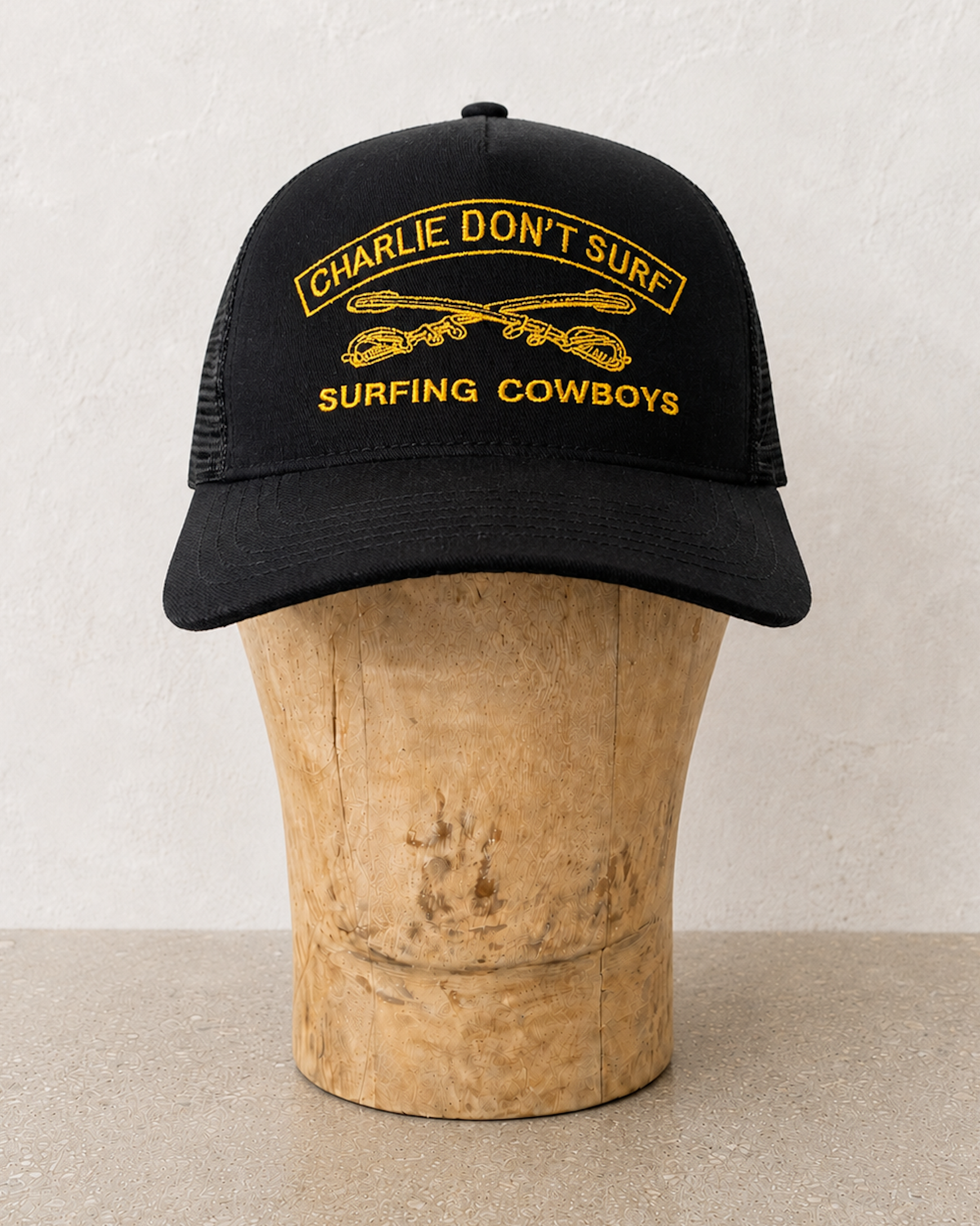 CHARLIE DON'T SURF BLACK AND GOLD CAP ON STAND
