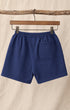 Back of Surfing Cowboys Relaxed Shorts in Loopback Cotton – Washed Navy on hanger in front of canvas background