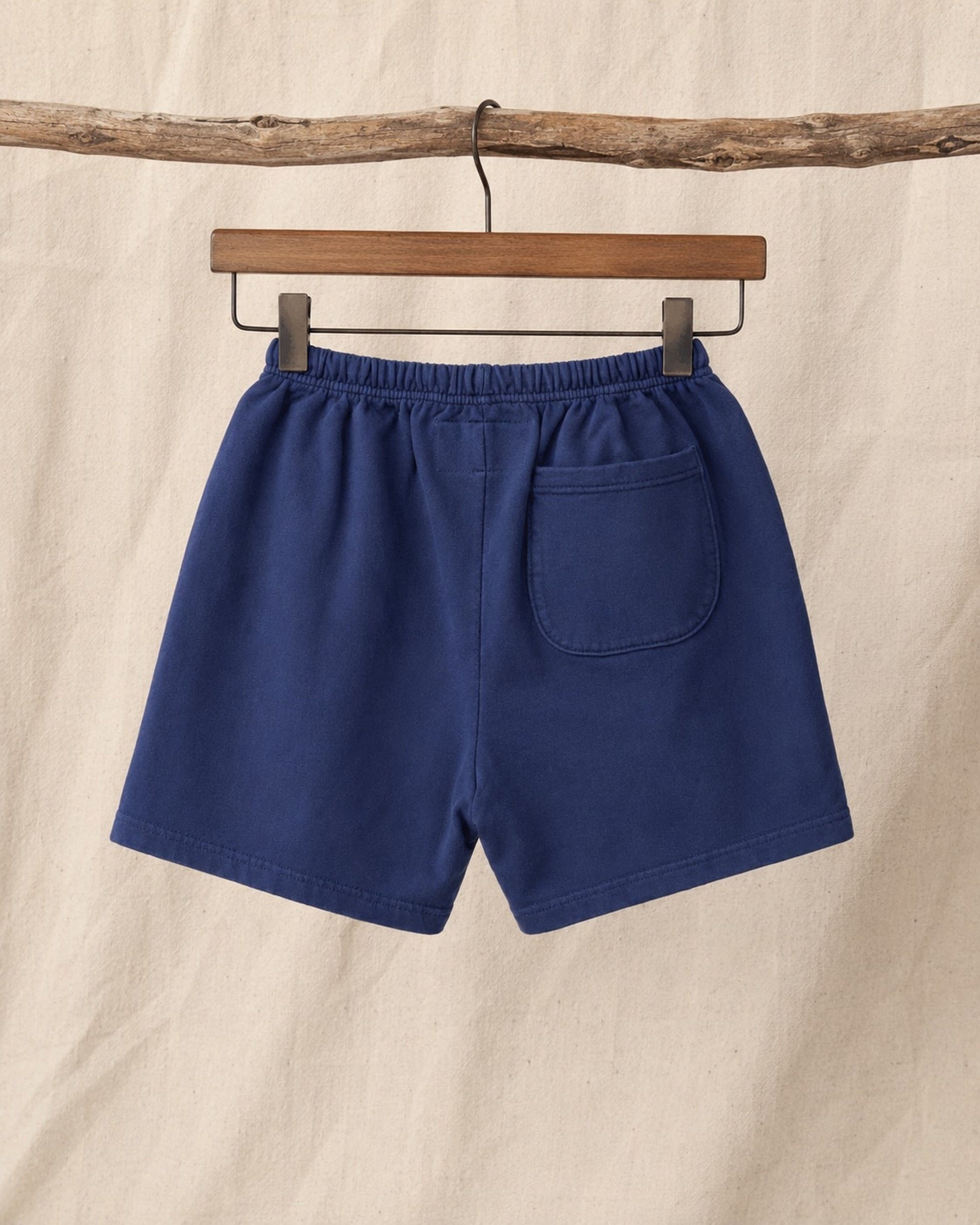 Back of Surfing Cowboys Relaxed Shorts in Loopback Cotton – Washed Navy on hanger in front of canvas background