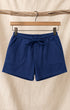 Front of Surfing Cowboys Relaxed Shorts in Loopback Cotton – Washed Navy on hanger in front of canvas background.