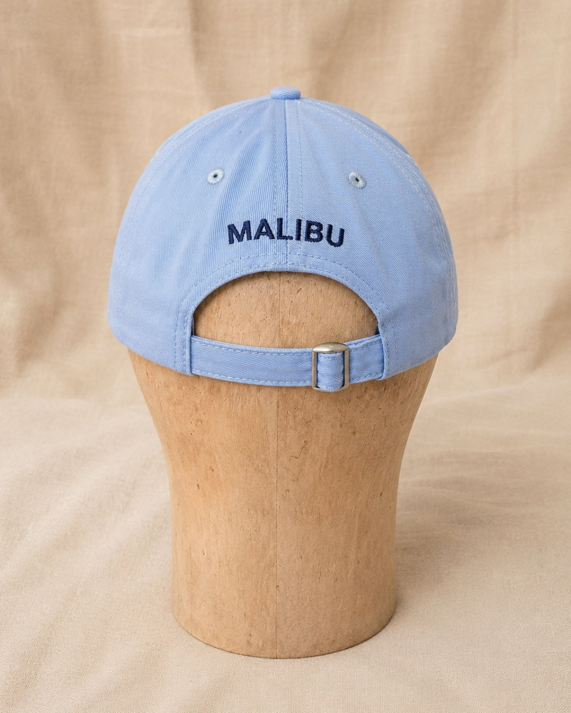 Back view of light blue Surfing Cowboys Rising Sun Cap with navy MALIBU embroidery and adjustable buckle strap.