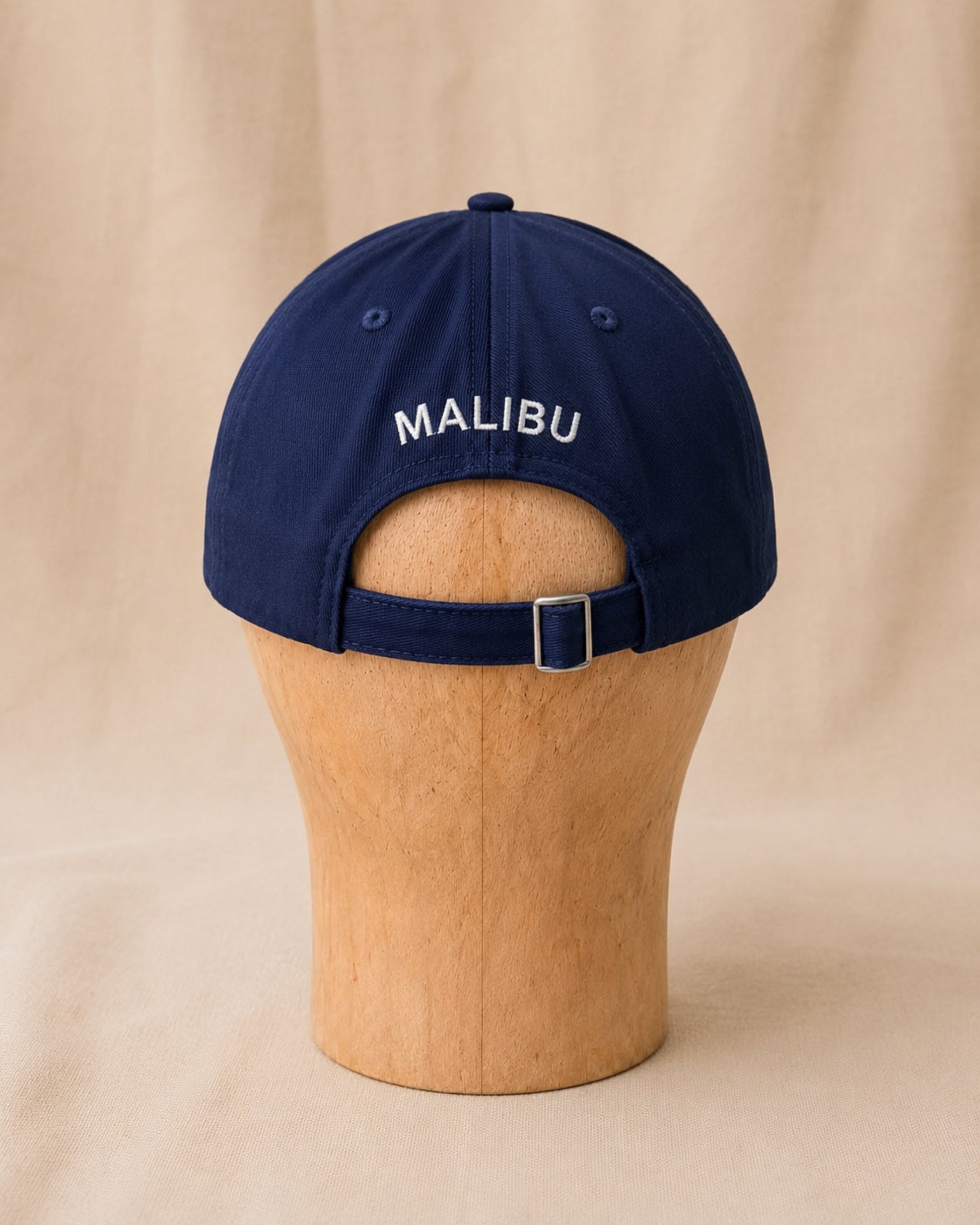 Back view of navy Surfing Cowboys Rising Sun Cap with creamy-white MALIBU embroidery and adjustable buckle strap.