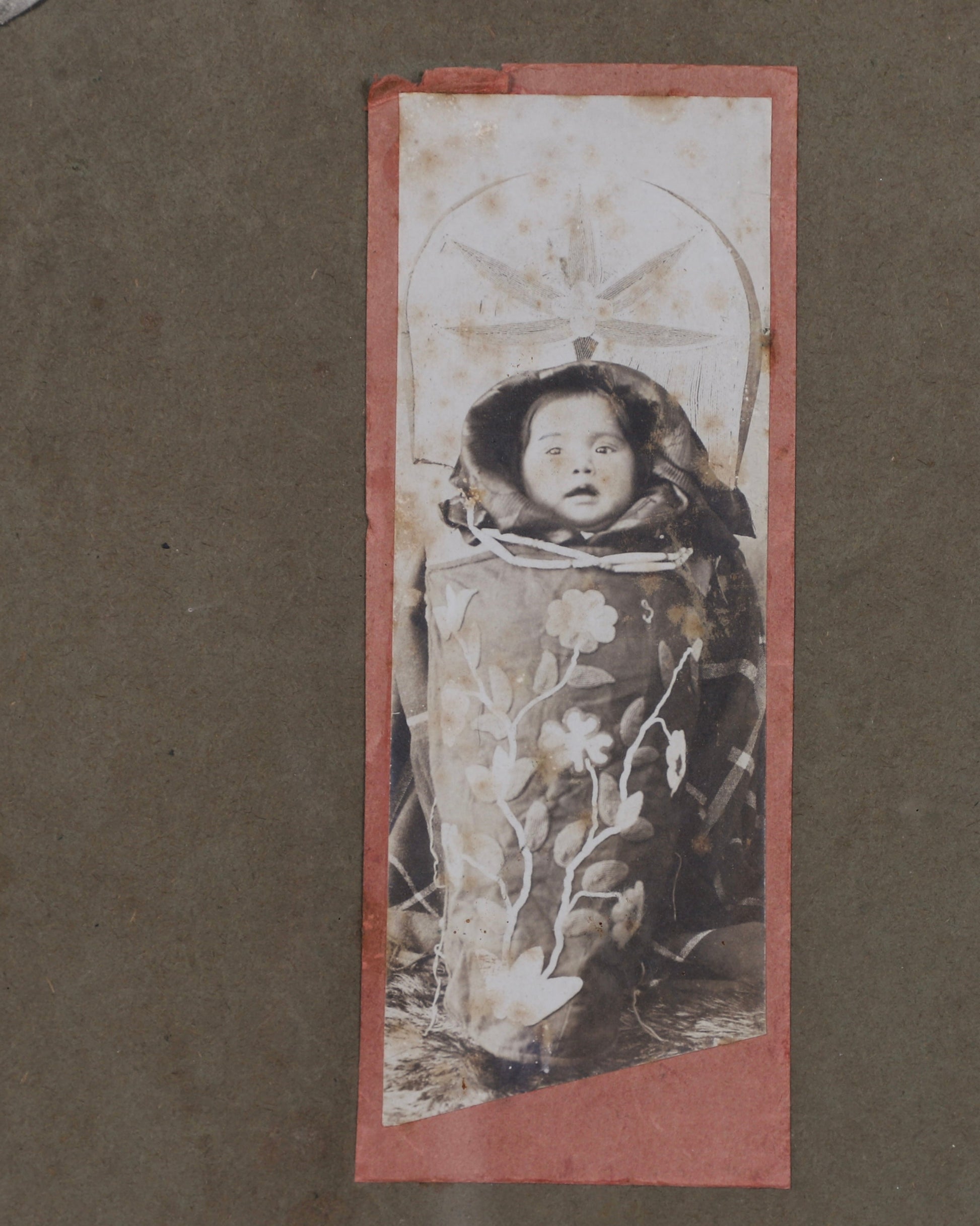 Detail of 19th-century photographic portrait showing an unidentified Native American  baby in traditional dress.